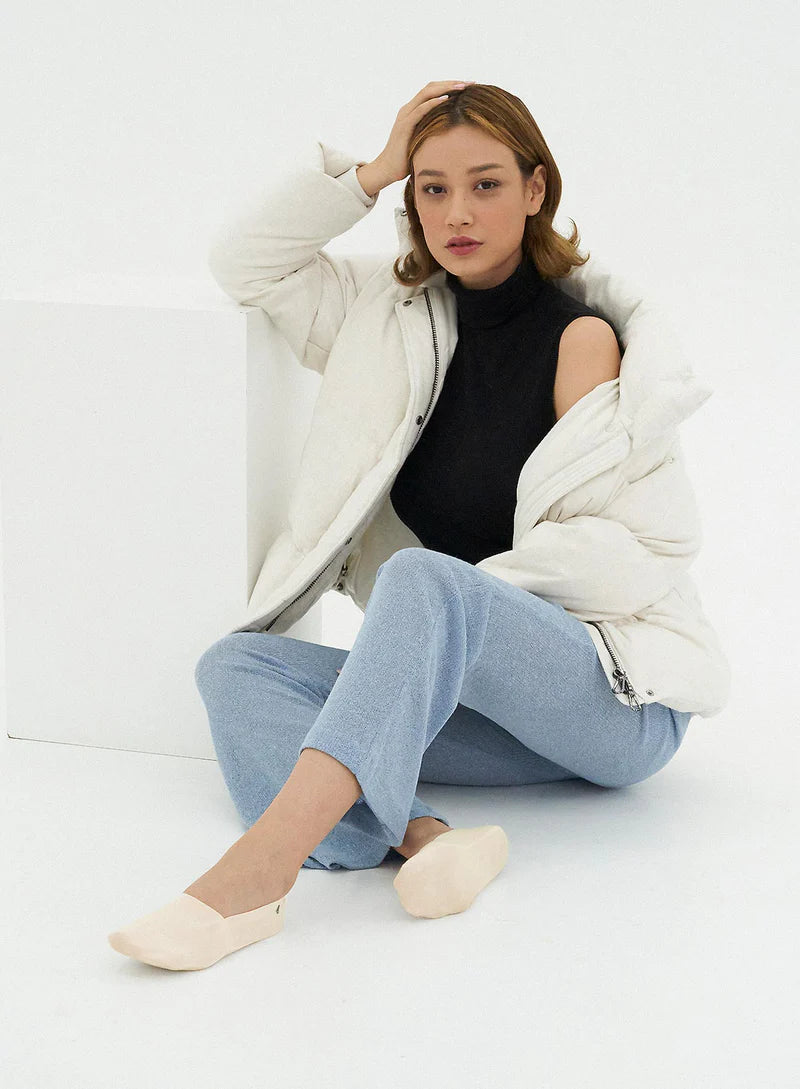 Femme assise en tenue décontractée portant des chaussettes invisibles beiges SOKA ONE – chaussettes fines, confortables et invisibles, parfaites pour un look élégant et naturel.